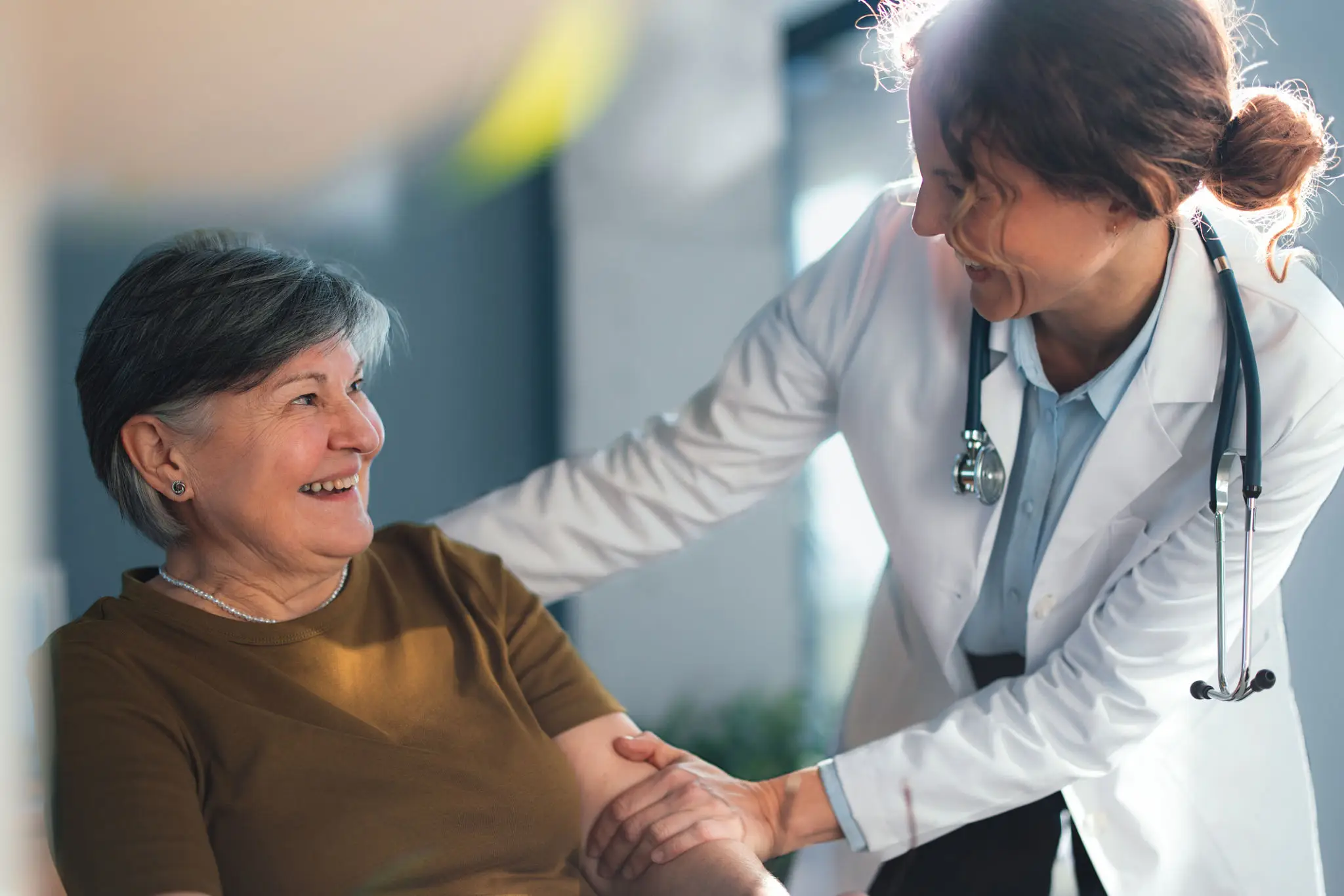 Female doctor comforting smiling elderly patient