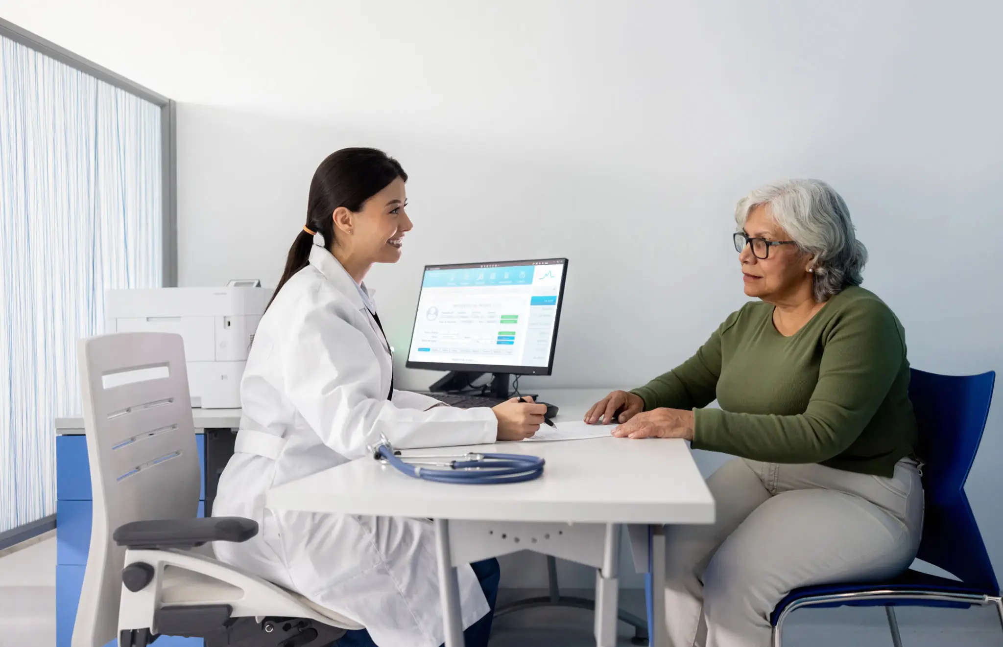 Doctor consulting senior patient at computer