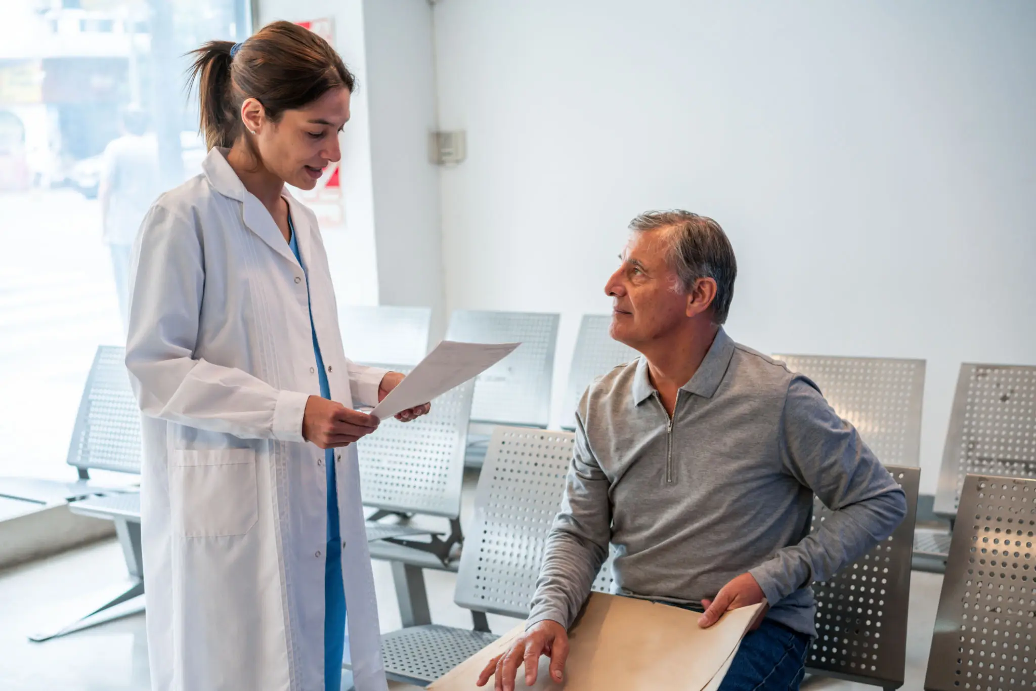 Doctor reviews documents with seated older patient