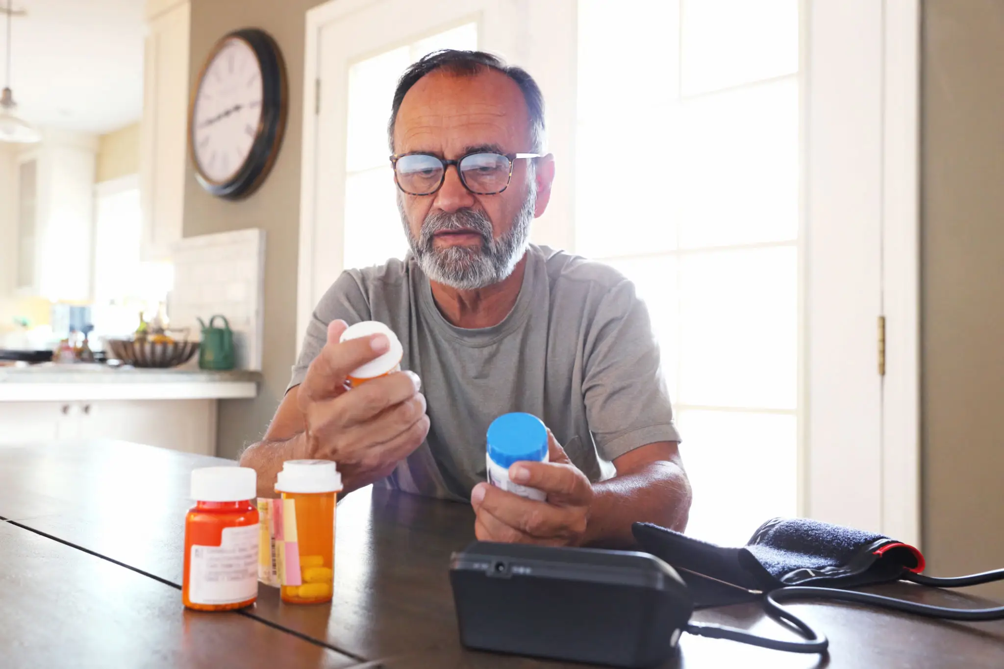 Man reading prescription bottles at kitchen table
