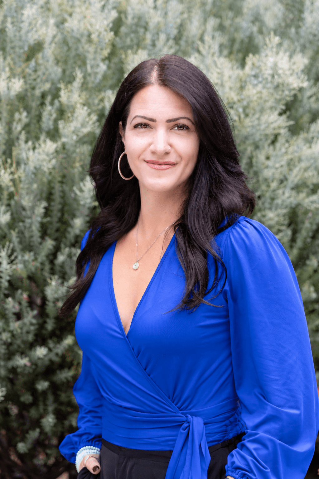Smiling woman in blue blouse, greenery background