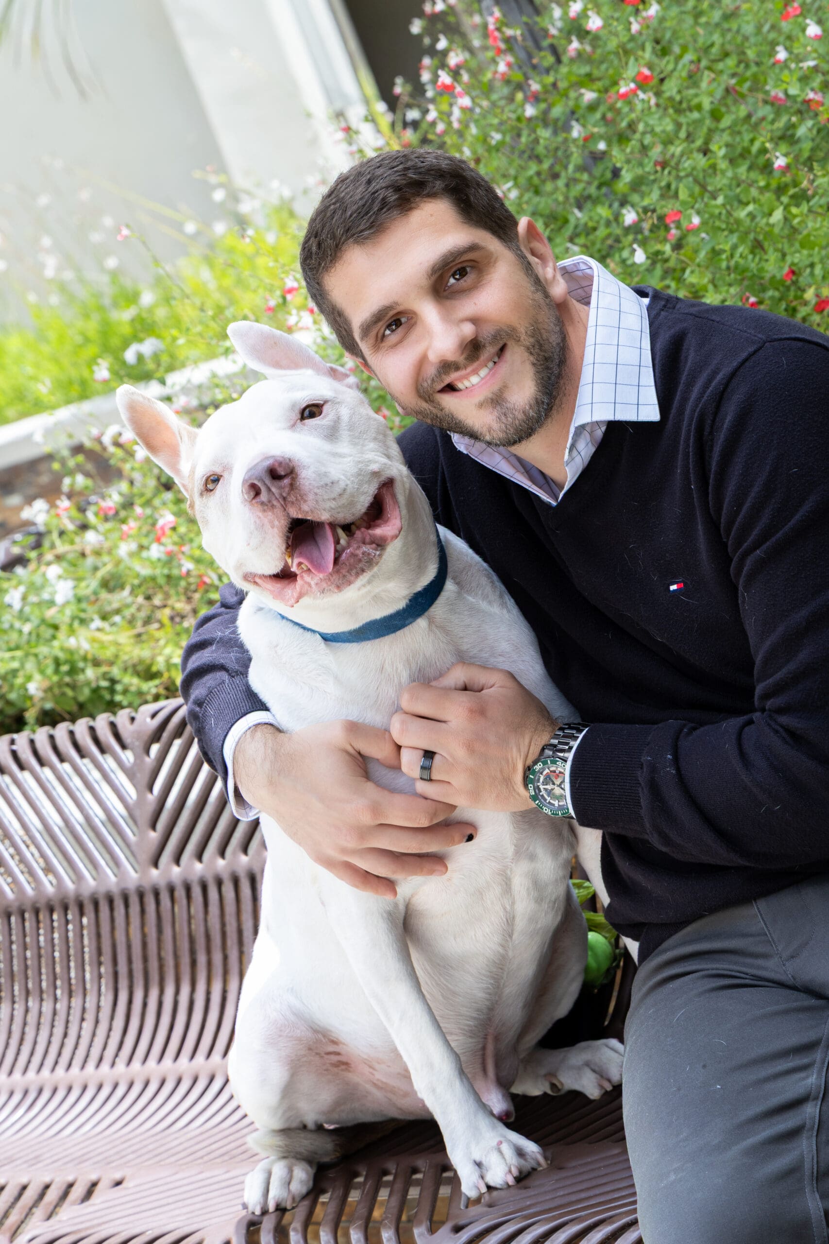 Smiling man hugging white dog on bench