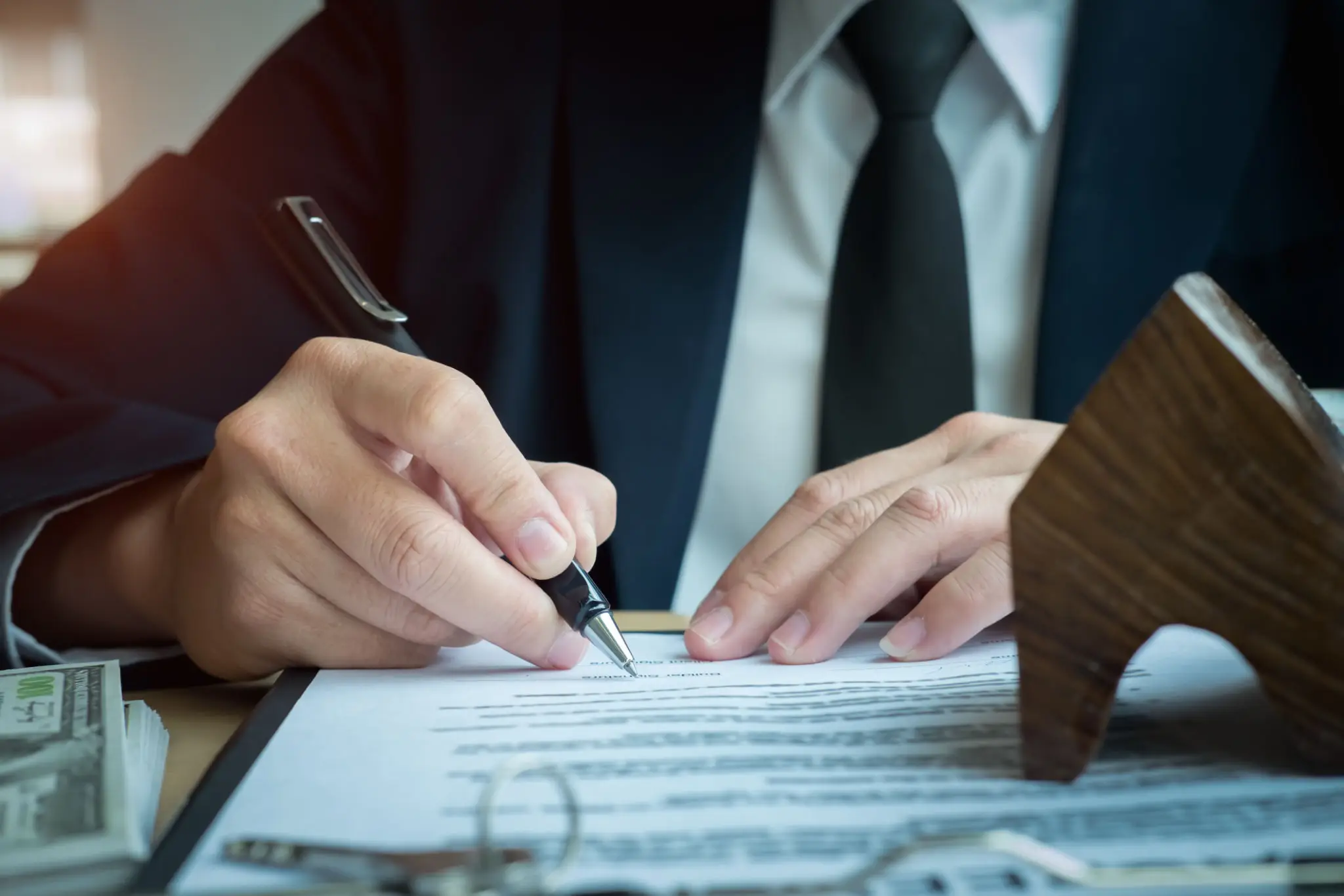 Person signing legal document beside gavel
