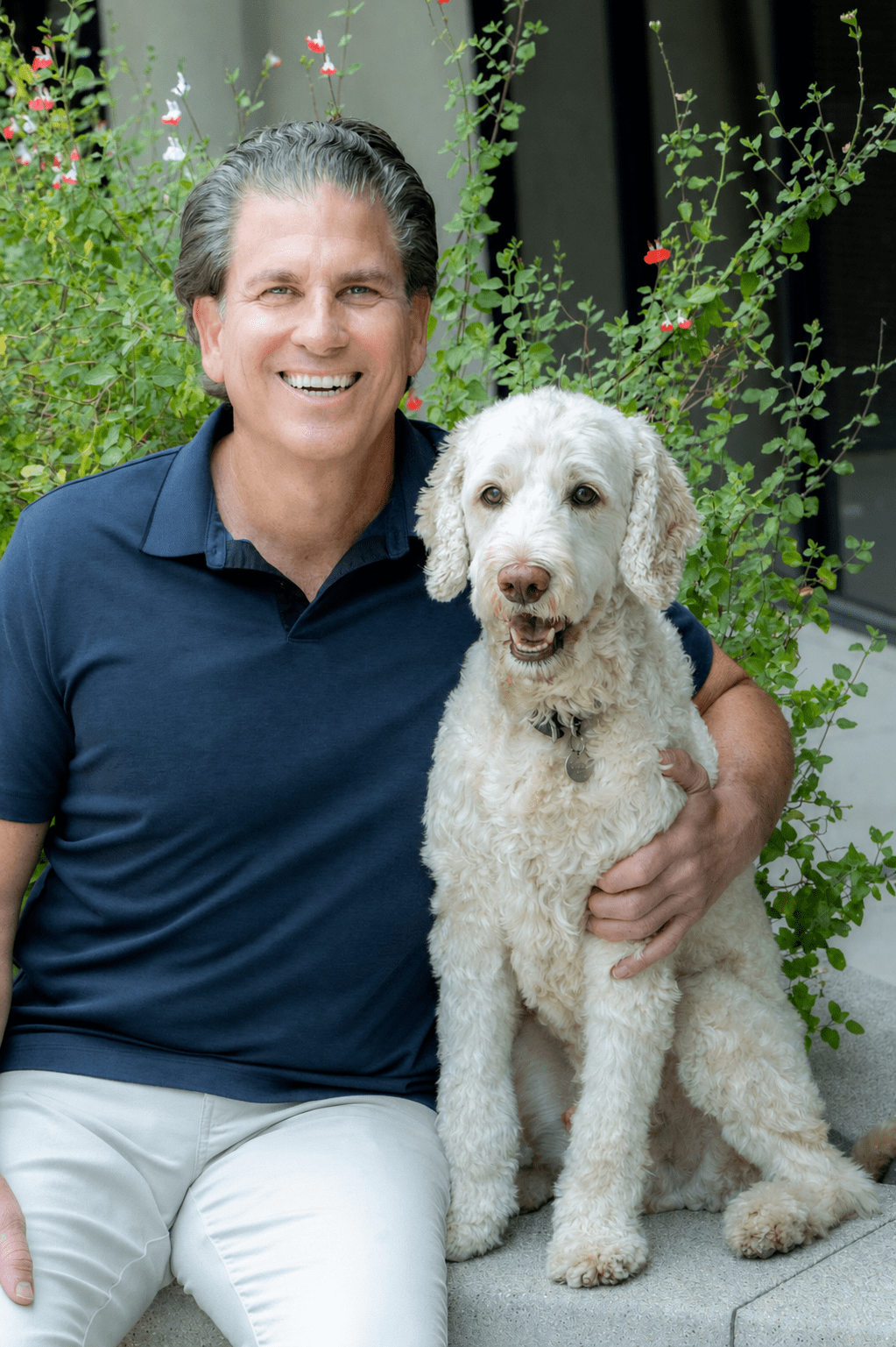 Smiling man with curly white dog outdoors
