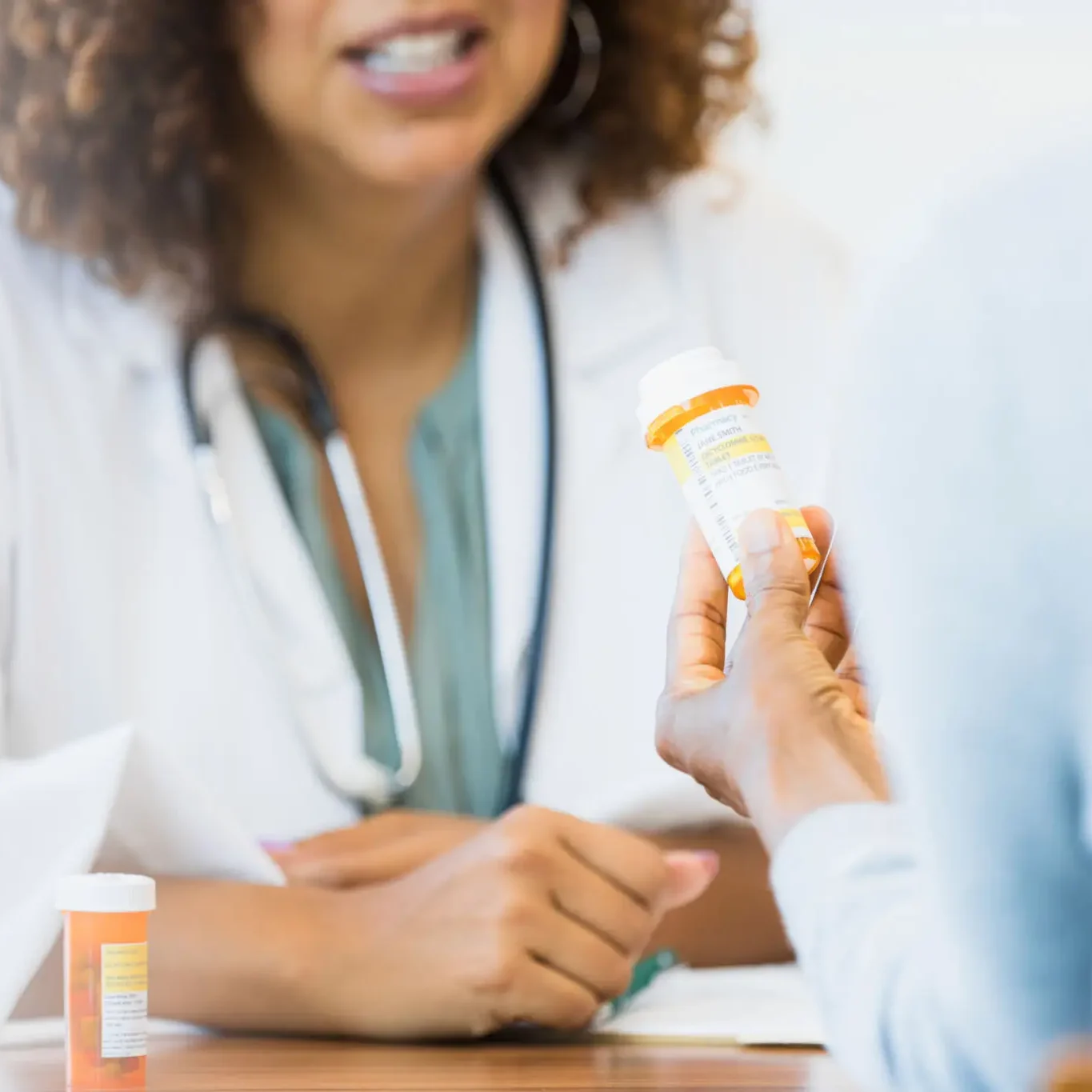 Doctor handing prescription bottle to patient