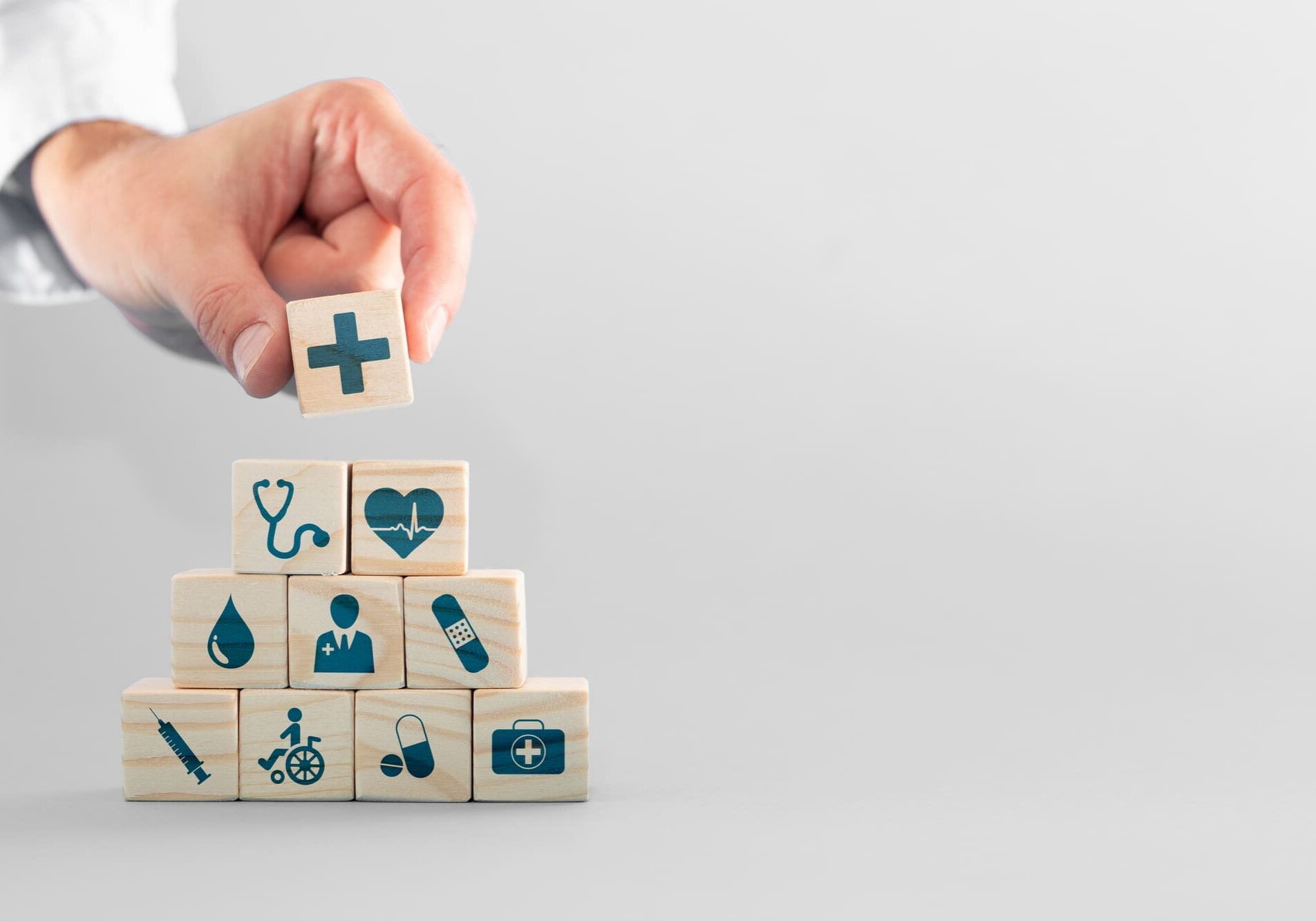 Hand arranging wood block with healthcare medical icon.