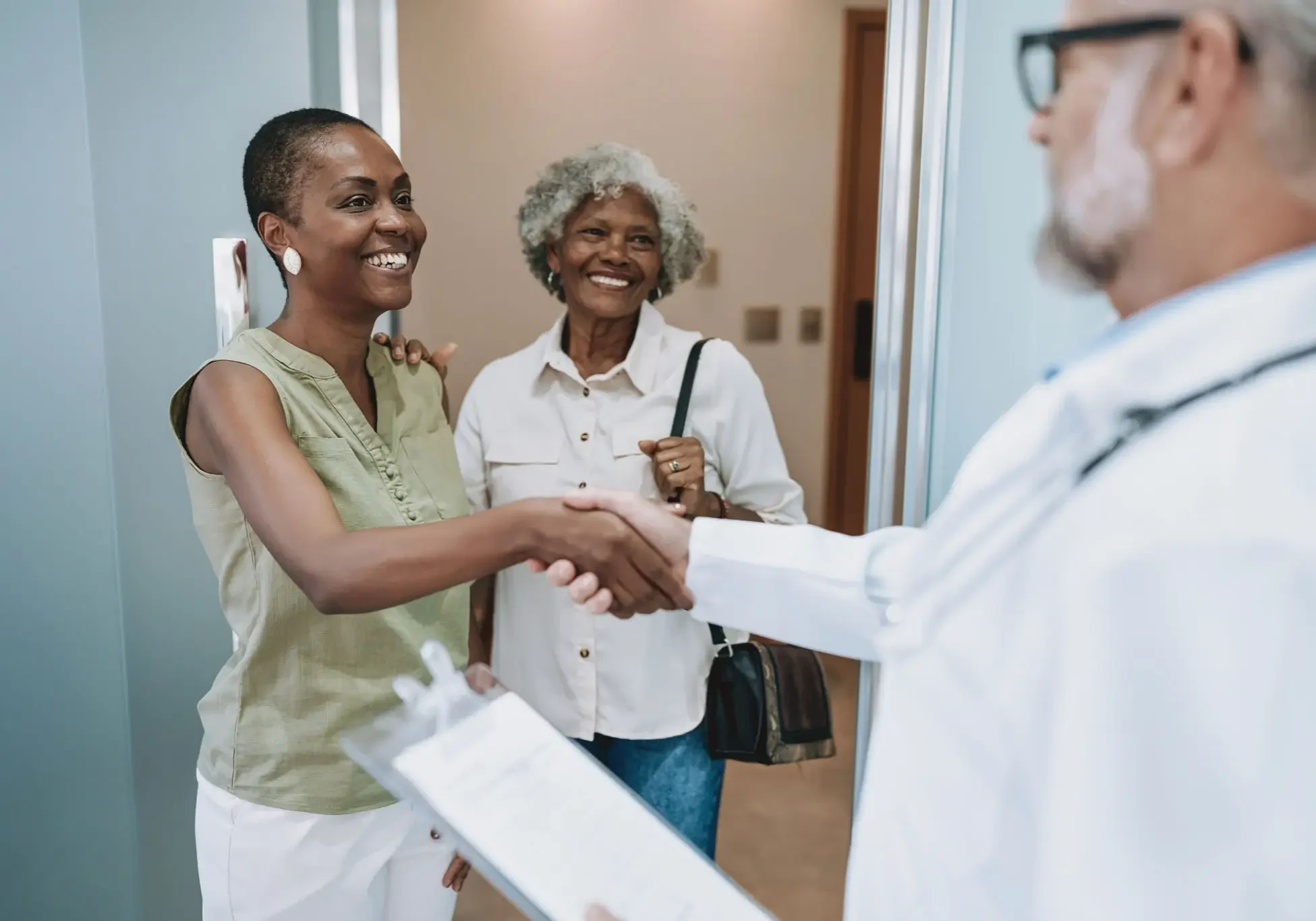 Patient and companion greeting doctor with handshake