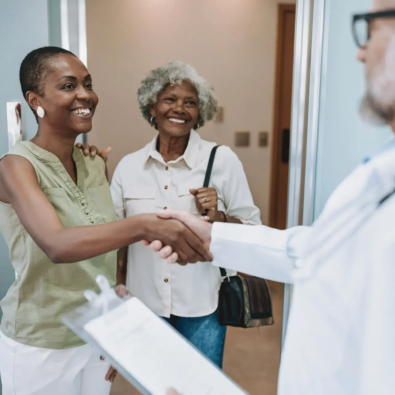 Patient and companion greeting doctor with handshake